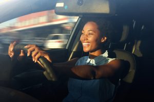 A woman smiling while driving a car.